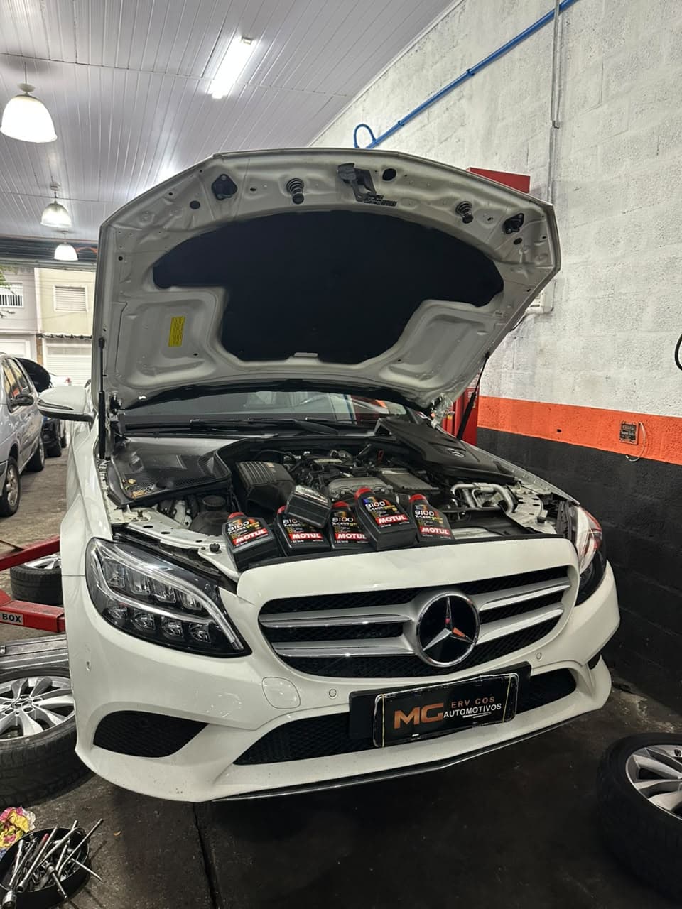 Mercedes-Benz branca com capô aberto na MG Serviços Automotivos, no Ipiranga, durante troca de óleo